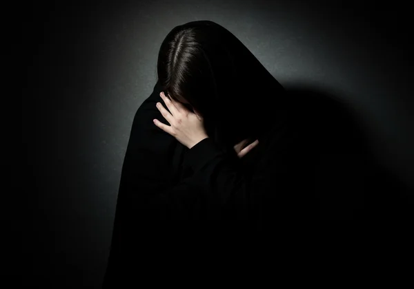 Person shrouded in shadow, reflecting shame and worthlessness